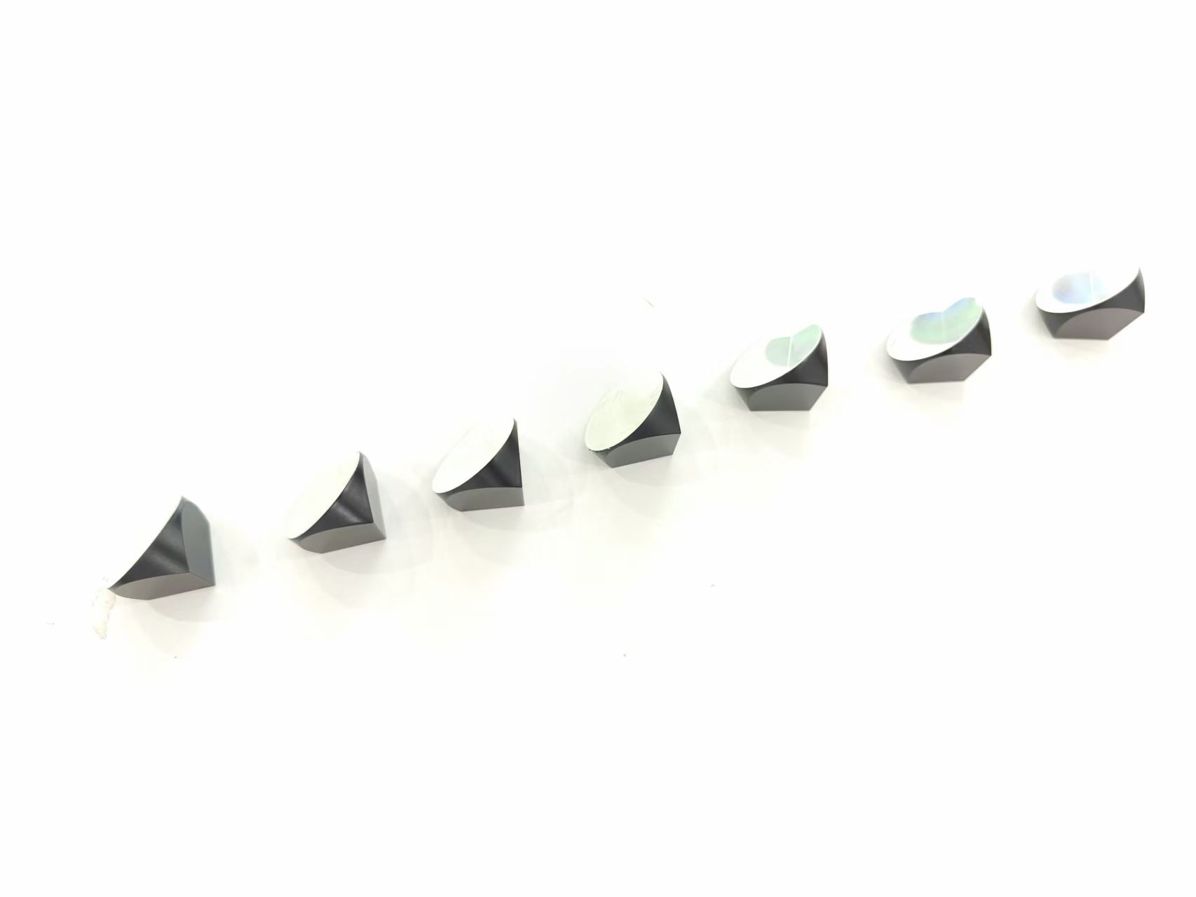 Array of optical prisms showcasing different angles and light reflections, including the 25.4mm Optical Mini Prism.